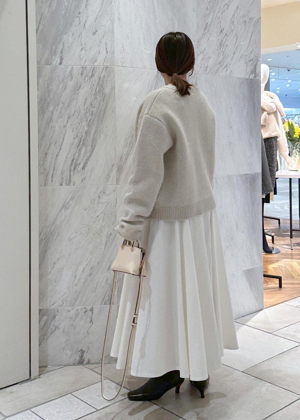 ベージュ系のショルダーバッグ、ホワイト系のカーディガン/ボレロ、ホワイト系のスカートを着用したレディースの冬コーディネートの3枚目の写真