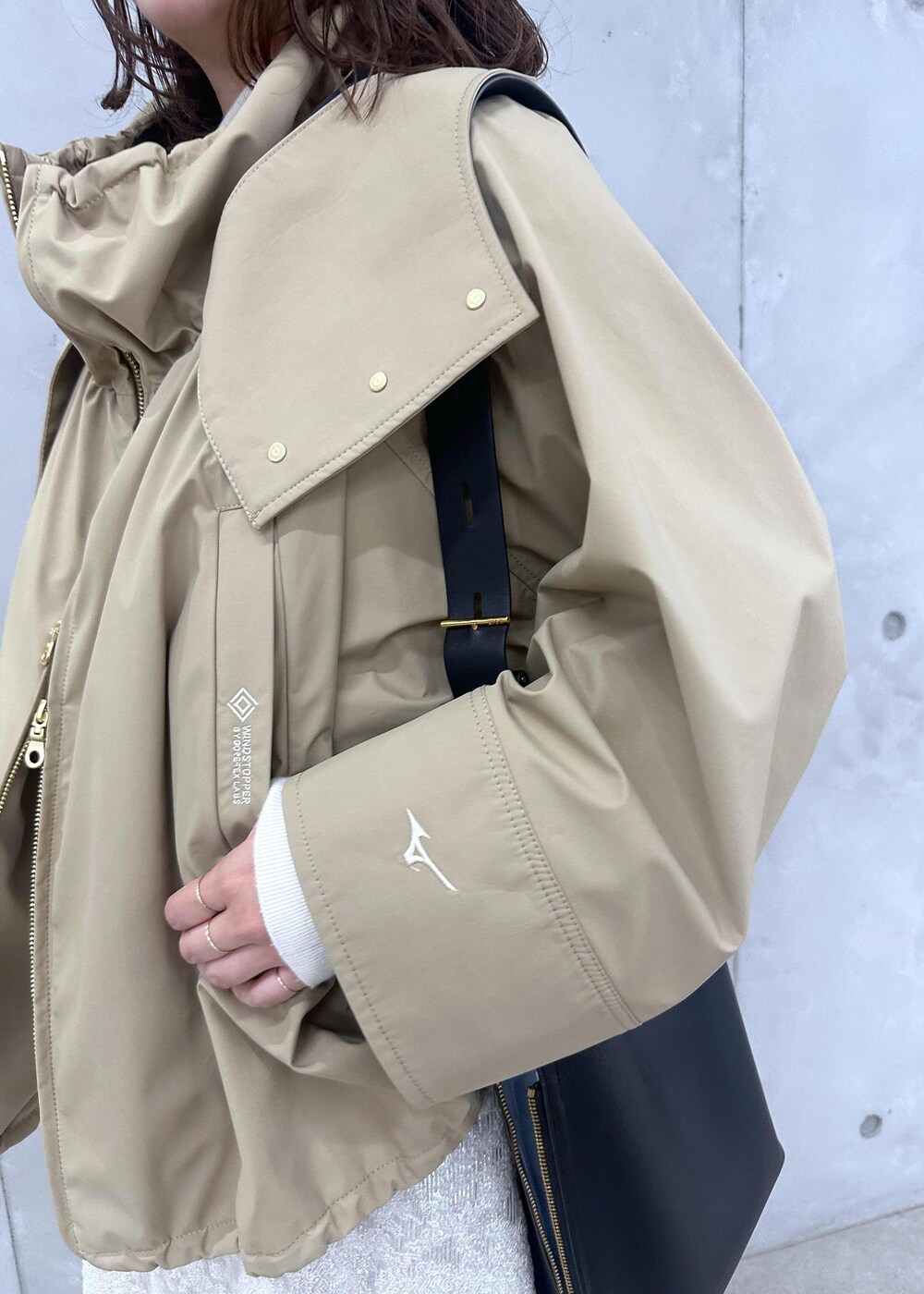 ブラック系のブーツ、ホワイト系のワンピース、ベージュ系のマウンテンパーカーを着用したレディースの秋コーディネートの6枚目の写真