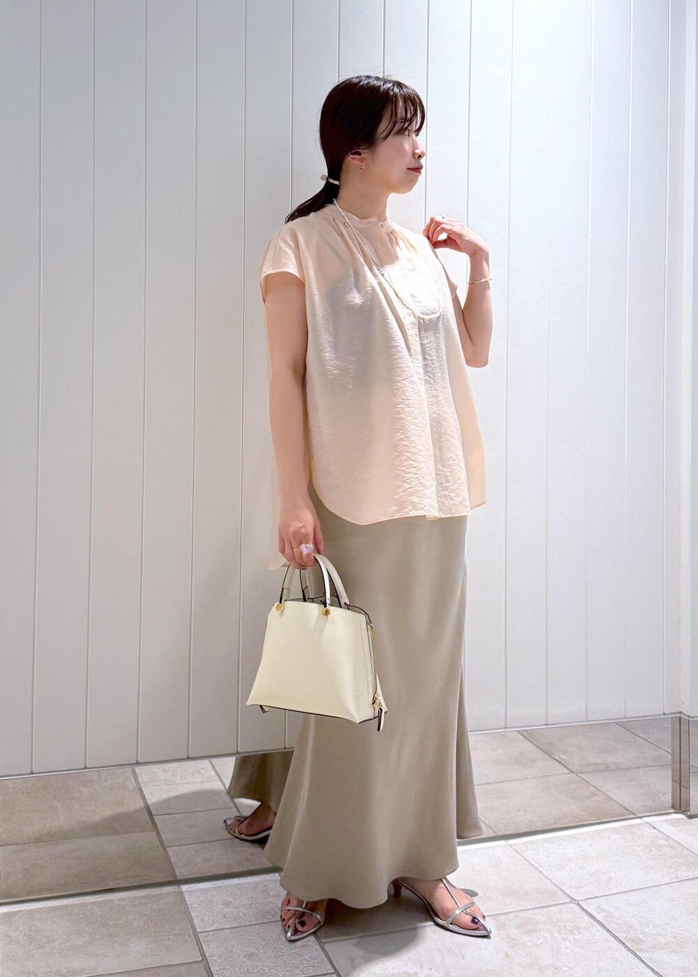 ベージュ系のスカート、ピンク系のシャツ/ブラウス、ホワイト系のハンドバッグを着用したレディースの夏コーディネートの2枚目の写真
