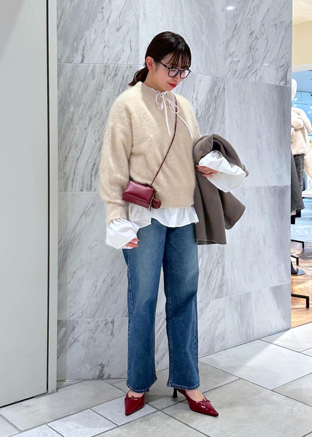 レッド系のパンプス、ベージュ系のニット/セーター、ベージュ系のピーコートを着用したレディースの冬コーディネートの2枚目の写真