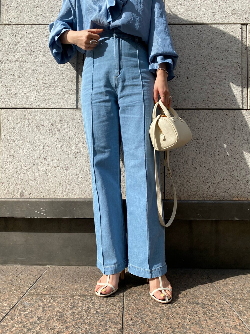 ブルー系のシャツ/ブラウス、ホワイト系のハンドバッグ、ブルー系のデニムパンツを着用したレディースの春コーディネートの4枚目の写真