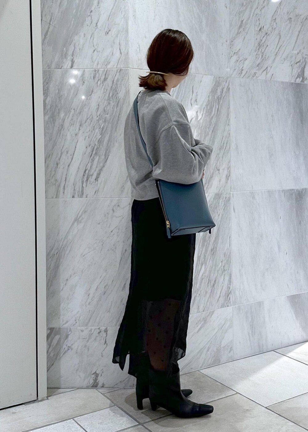 グレー系のスウェット、ブルー系のショルダーバッグ、ブラック系のスカートを着用したレディースの秋コーディネートの3枚目の写真