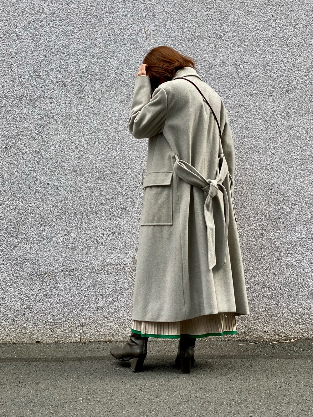 グレー系のチェスターコート、ベージュ系のスカート、ブラウン系のブーツを着用したレディースの冬コーディネートの4枚目の写真