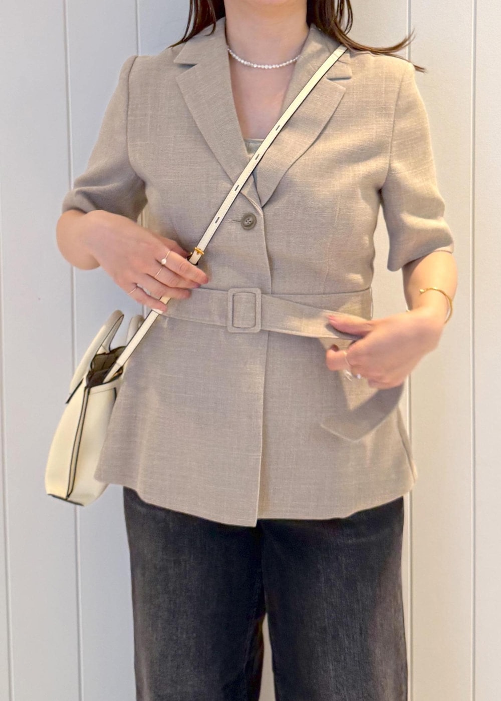ベージュ系のテーラードジャケット、ブラック系のデニムパンツ、ホワイト系のショルダーバッグを着用したレディースの夏コーディネートの7枚目の写真