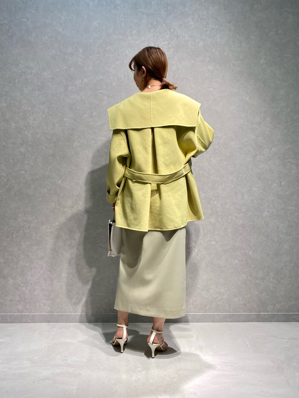 ブルー系のTシャツ/カットソー、イエロー系のトレンチコート、ベージュ系のスカートを着用したレディースの春コーディネートの2枚目の写真