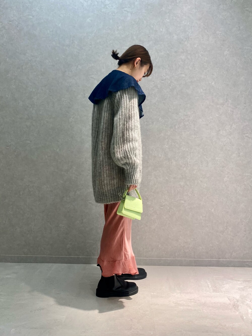 グレー系のニット/セーター、ブルー系のシャツ/ブラウス、グリーン系のバッグを着用したレディースの冬コーディネートの2枚目の写真