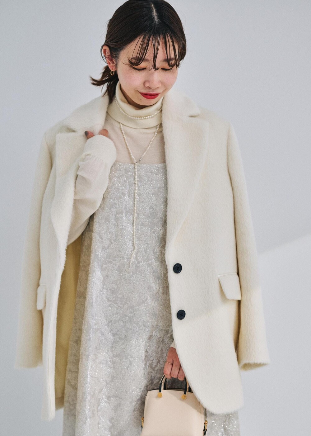 ベージュ系のショルダーバッグ、ブラック系のブーツ、ホワイト系のテーラードジャケットを着用したレディースの冬コーディネートの3枚目の写真