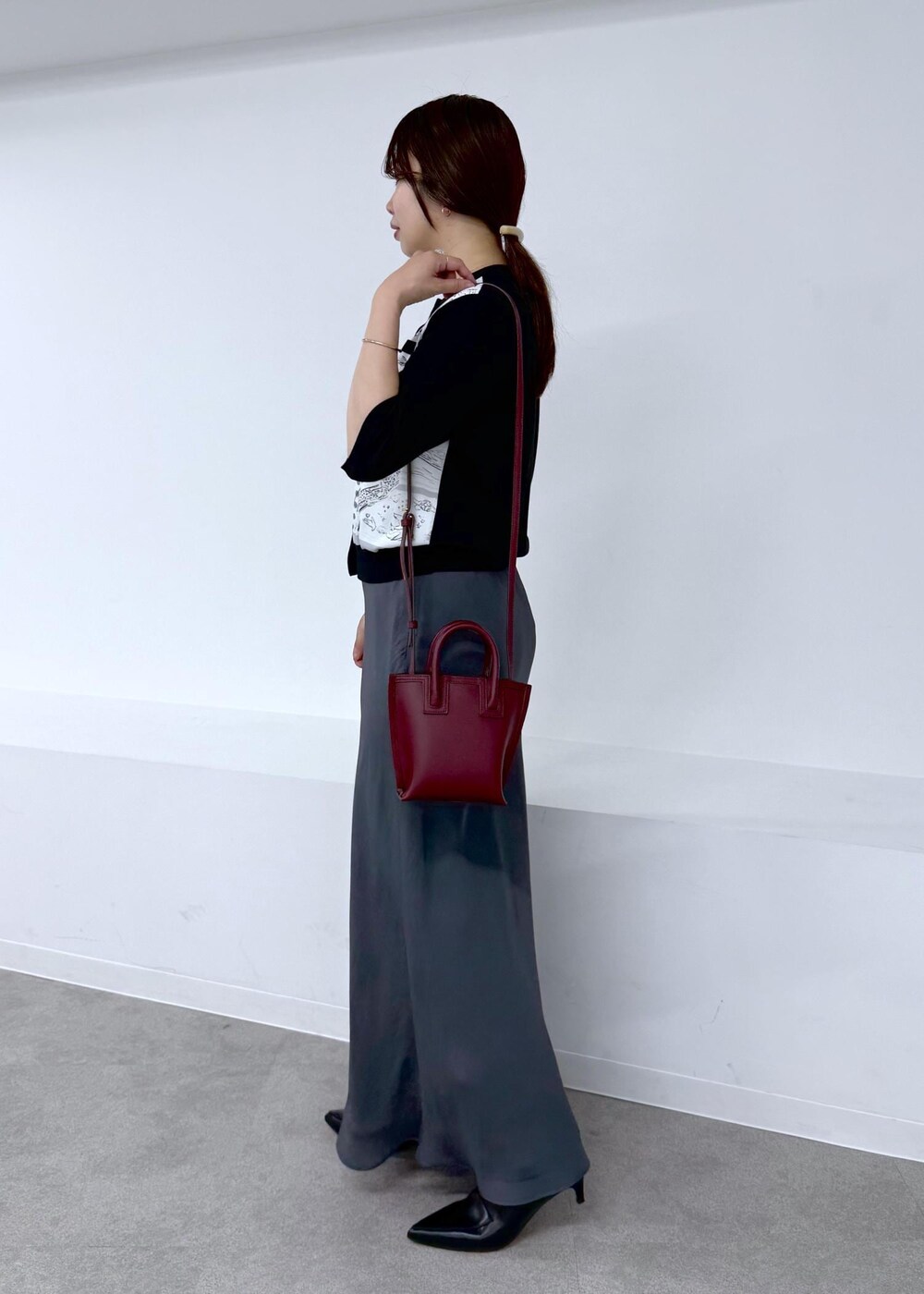 グレー系のスカート、ブラック系のシャツ/ブラウス、レッド系のショルダーバッグを着用したレディースの夏コーディネートの2枚目の写真