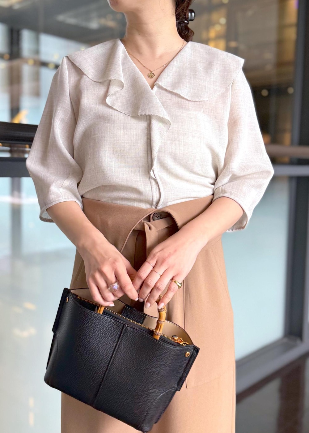ブラック系のハンドバッグ、ベージュ系のシャツ/ブラウス、ブラウン系のその他パンツを着用したレディースの春コーディネートの4枚目の写真