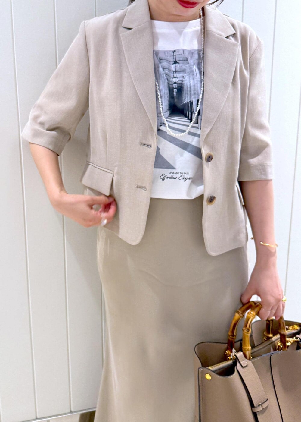 ベージュ系のトートバッグ、ホワイト系のTシャツ/カットソー、ベージュ系のスカートを着用したレディースの春コーディネートの6枚目の写真