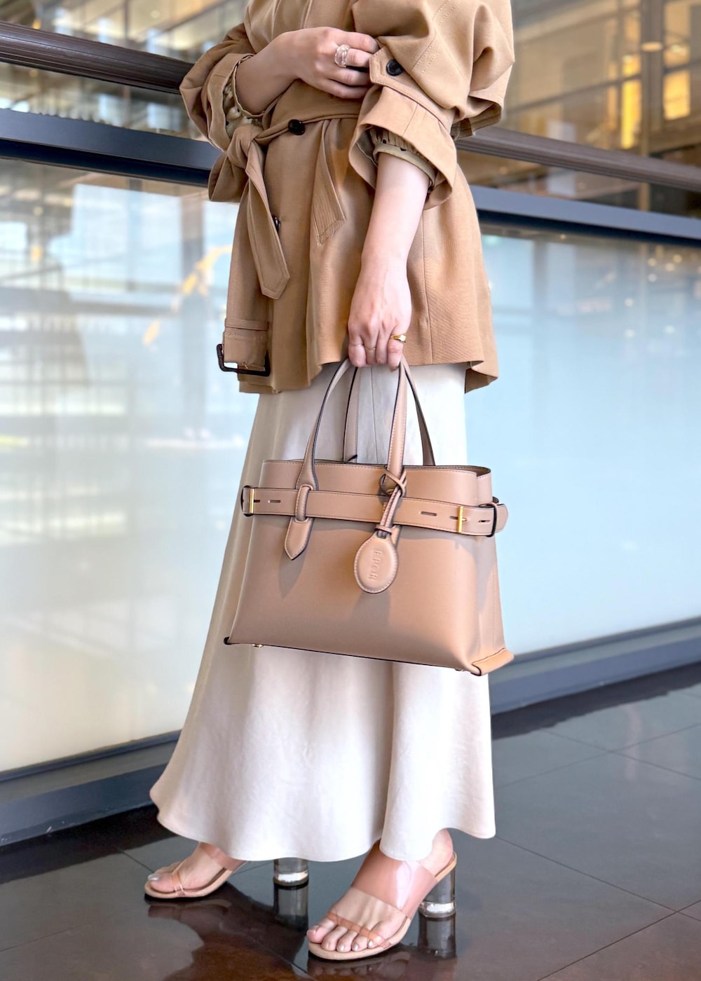 ベージュ系のトレンチコート、ベージュ系のスカート、ベージュ系のシャツ/ブラウスを着用したレディースの春コーディネートの6枚目の写真