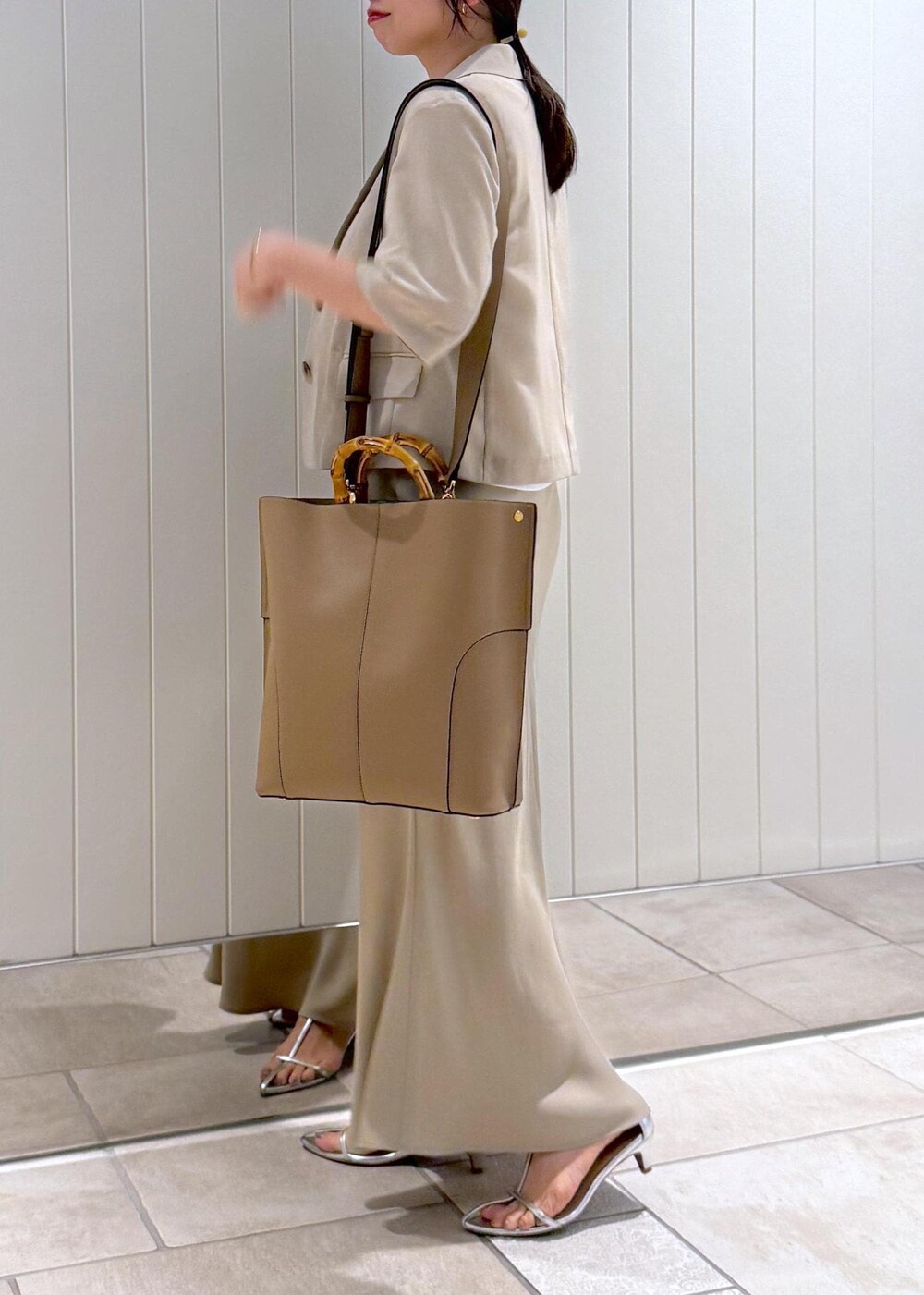 ベージュ系のトートバッグ、ホワイト系のTシャツ/カットソー、ベージュ系のスカートを着用したレディースの春コーディネートの5枚目の写真