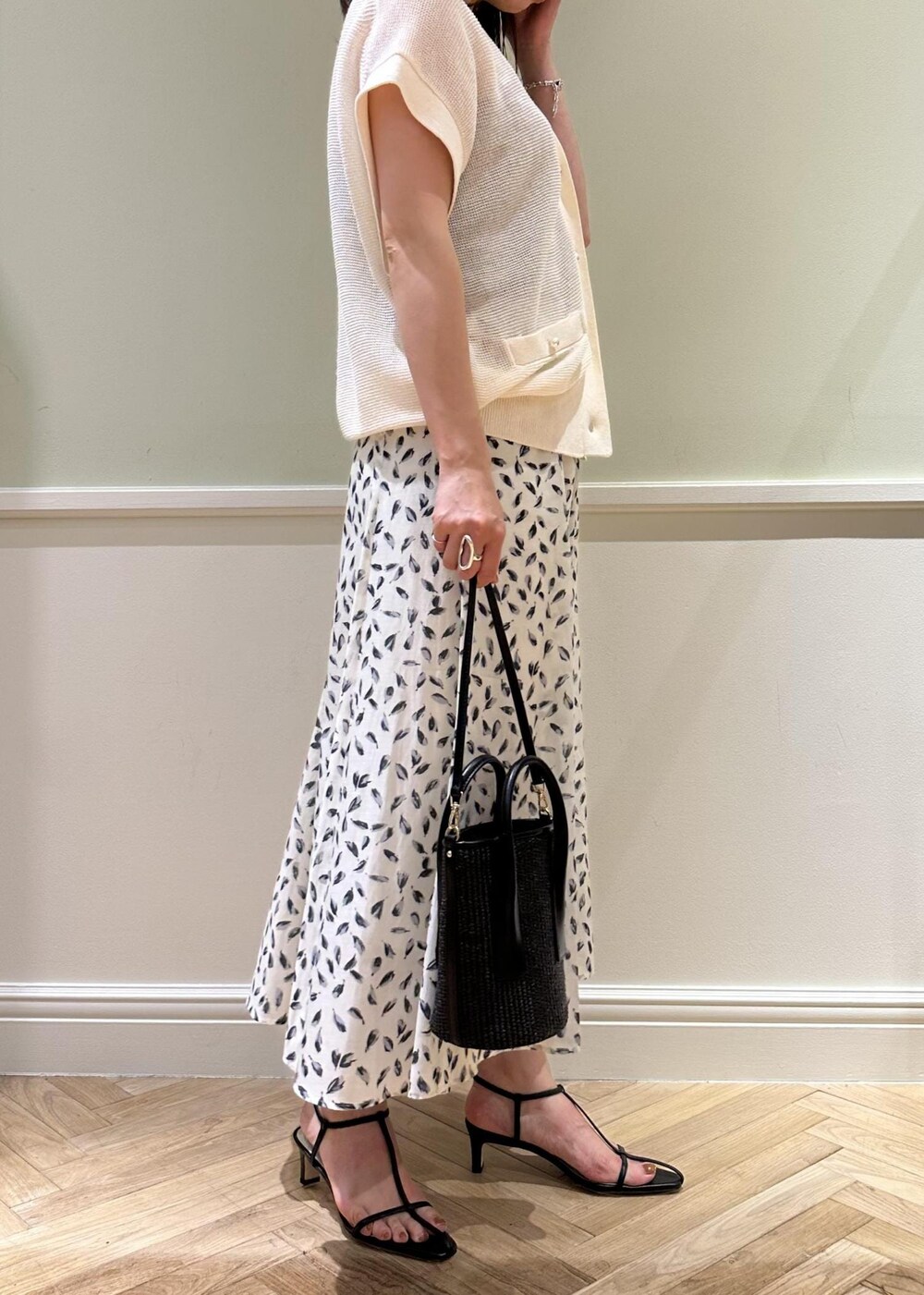 ブラック系のハンドバッグ、ホワイト系のスカート、ブラック系のサンダルを着用したレディースの夏コーディネートの3枚目の写真