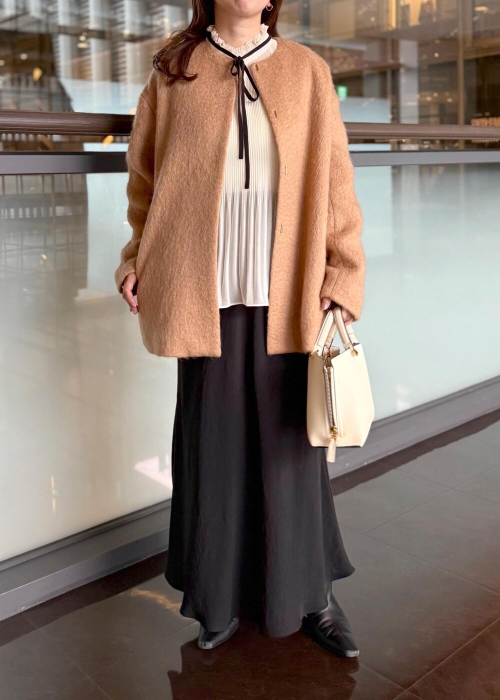 ホワイト系のハンドバッグ、ブラック系のスカート、ホワイト系のシャツ/ブラウスを着用したレディースの秋コーディネートの4枚目の写真