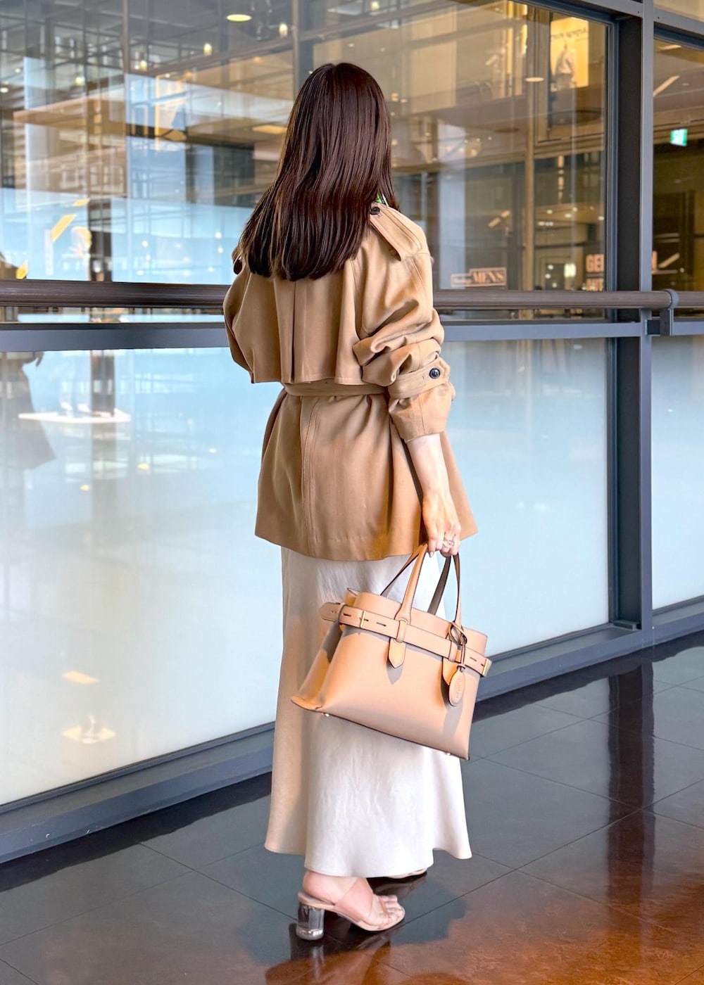 ベージュ系のトレンチコート、ベージュ系のスカート、ベージュ系のシャツ/ブラウスを着用したレディースの春コーディネートの2枚目の写真