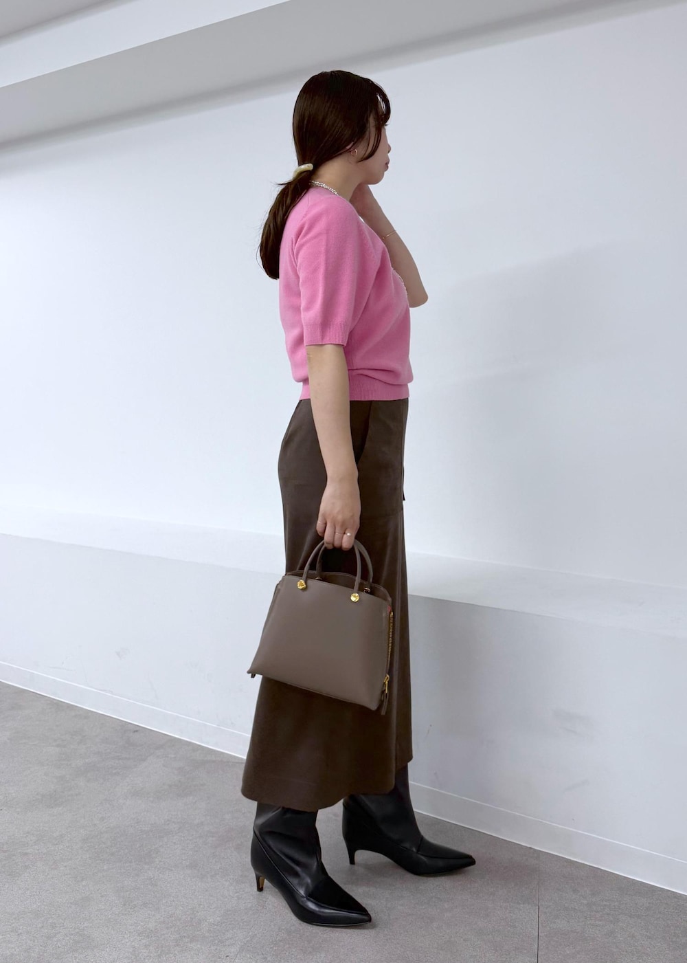 ブラック系のブーツ、ブラウン系のスカート、ブラウン系のハンドバッグを着用したレディースの秋コーディネートの3枚目の写真