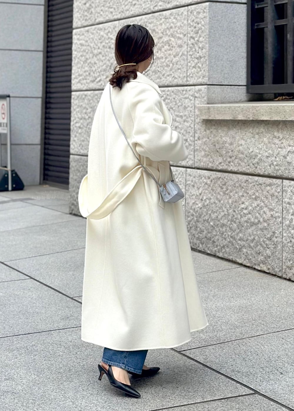 ブルー系のショルダーバッグ、ホワイト系のチェスターコート、ホワイト系のニット/セーターを着用したレディースの冬コーディネートの2枚目の写真