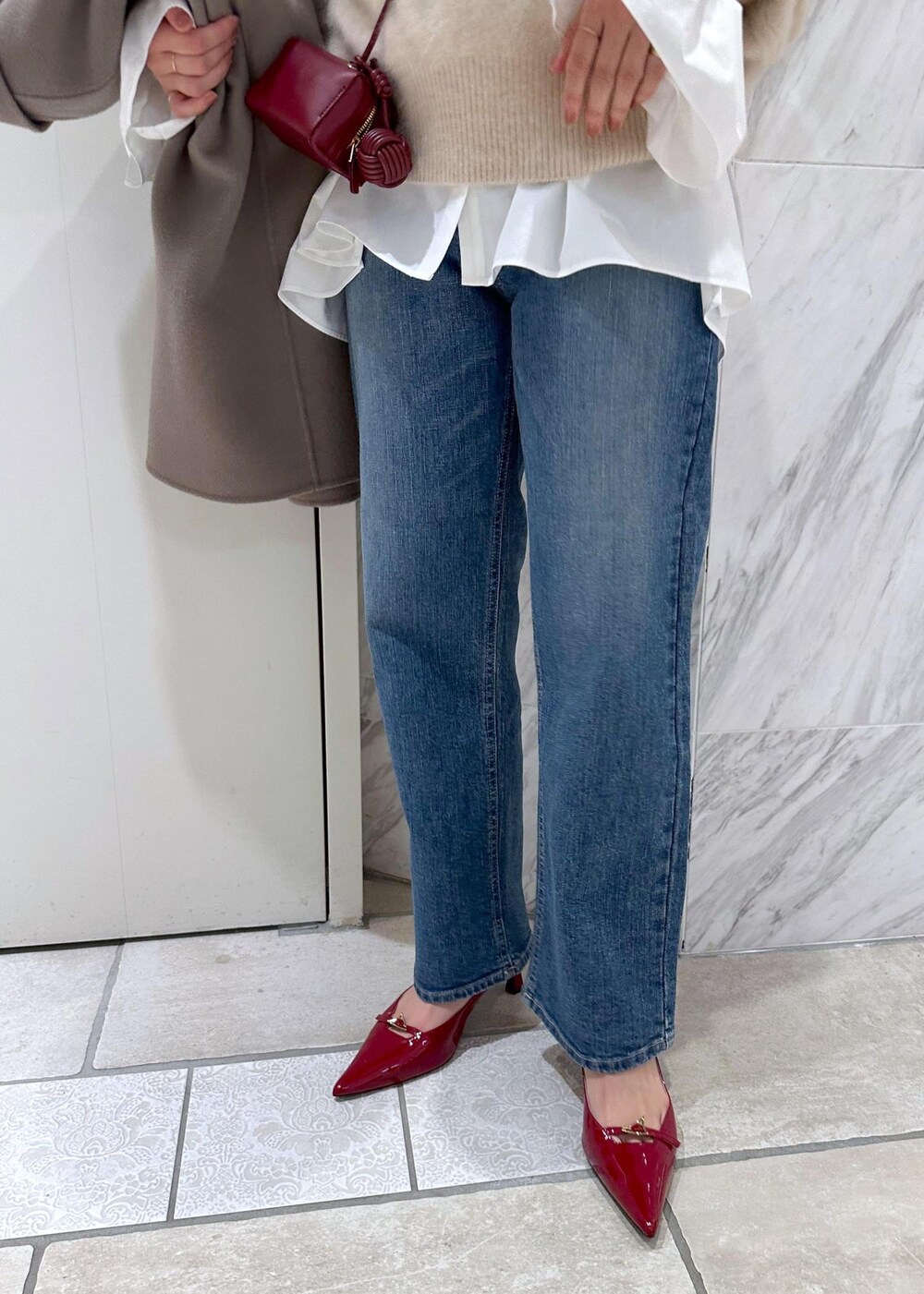 レッド系のパンプス、ベージュ系のニット/セーター、ベージュ系のピーコートを着用したレディースの冬コーディネートの7枚目の写真