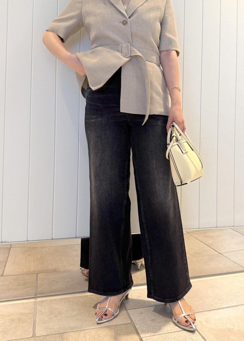 ベージュ系のテーラードジャケット、ブラック系のデニムパンツ、ホワイト系のショルダーバッグを着用したレディースの夏コーディネートの8枚目の写真