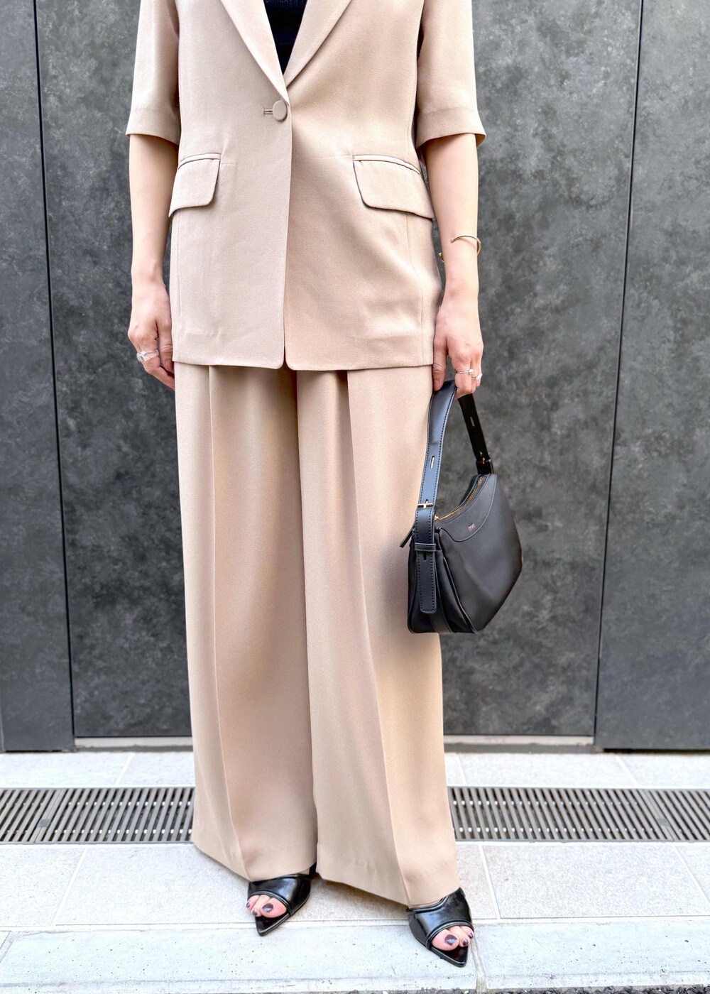 ベージュ系のその他パンツ、ベージュ系のテーラードジャケット、ブラック系のハンドバッグを着用したレディースの夏コーディネートの6枚目の写真