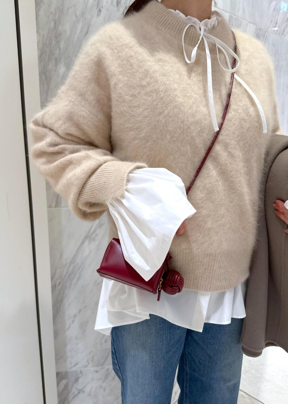 レッド系のパンプス、ベージュ系のニット/セーター、ベージュ系のピーコートを着用したレディースの冬コーディネートの6枚目の写真