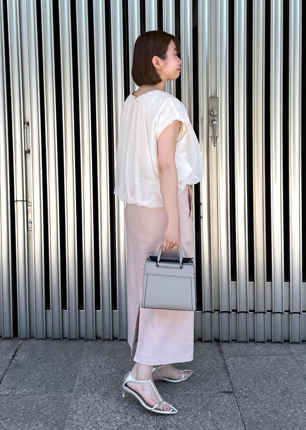 ピンク系のスカート、ホワイト系のTシャツ/カットソー、グレー系のハンドバッグを着用したレディースの夏コーディネートの3枚目の写真