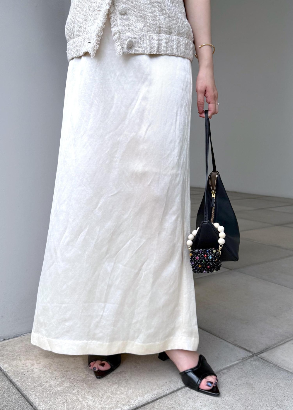 ホワイト系のスカート、ホワイト系のベストを着用したレディースの夏コーディネートの6枚目の写真