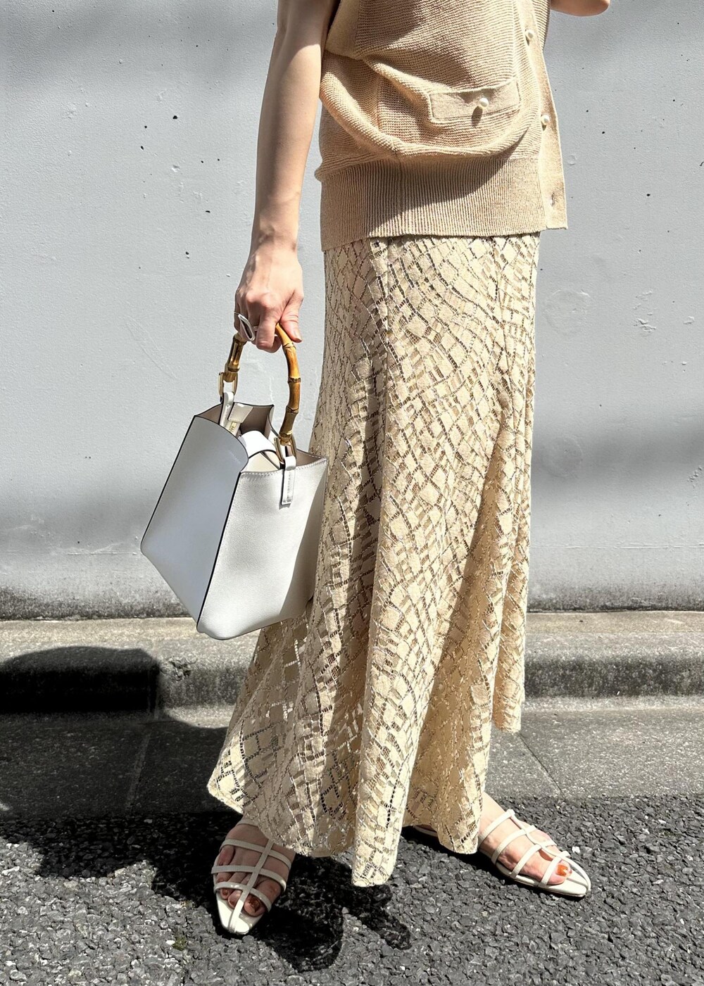 ベージュ系のスカート、ホワイト系のハンドバッグ、ホワイト系のサンダルを着用したレディースの春コーディネートの6枚目の写真