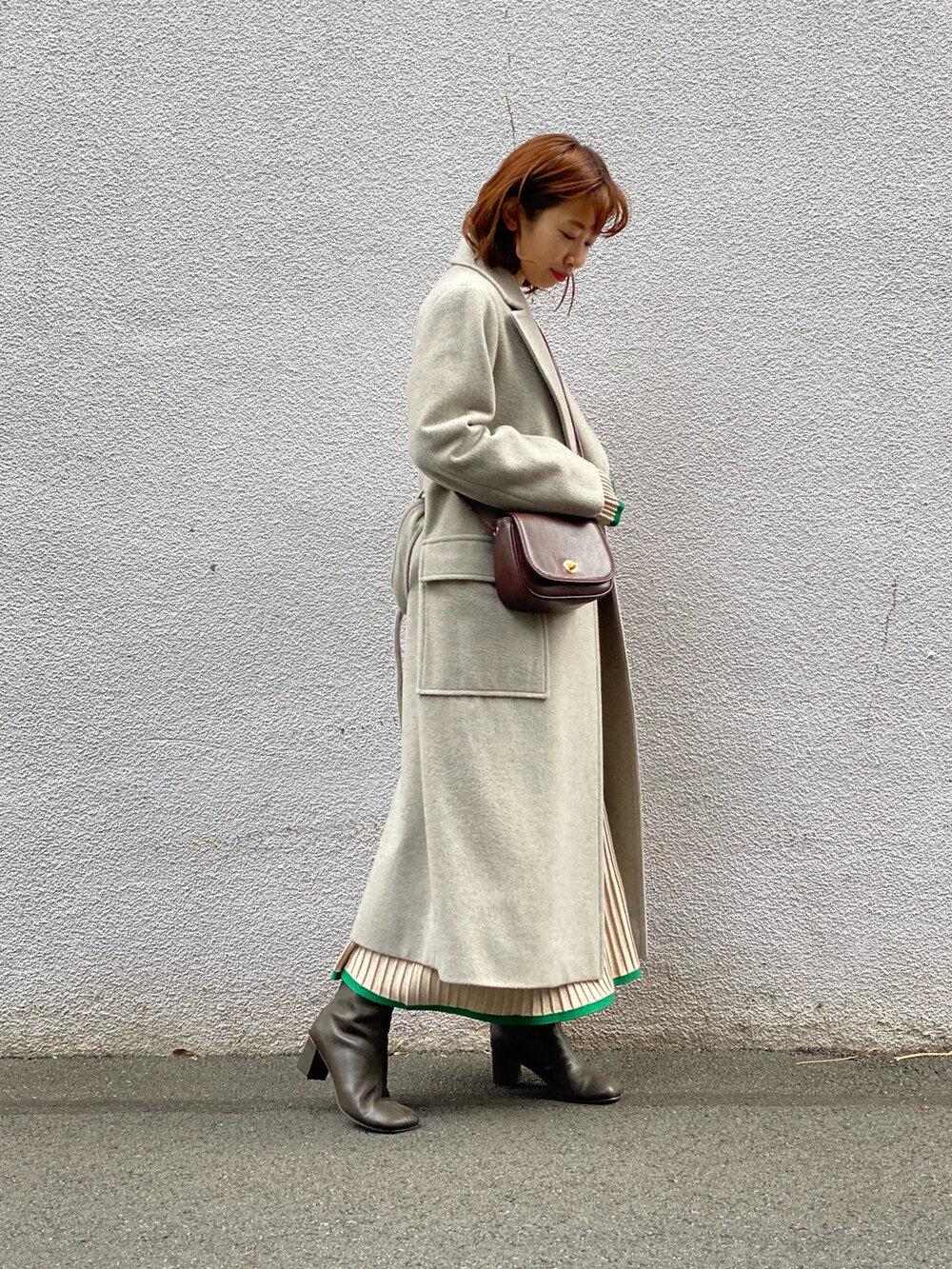 グレー系のチェスターコート、ベージュ系のスカート、ブラウン系のブーツを着用したレディースの冬コーディネートの3枚目の写真