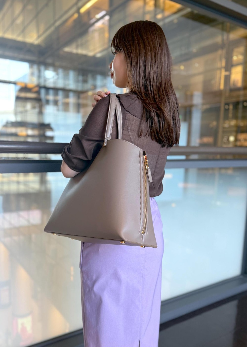 ブラウン系のトートバッグ、パープル系のスカート、ブラウン系のシャツ/ブラウスを着用したレディースの春コーディネートの5枚目の写真