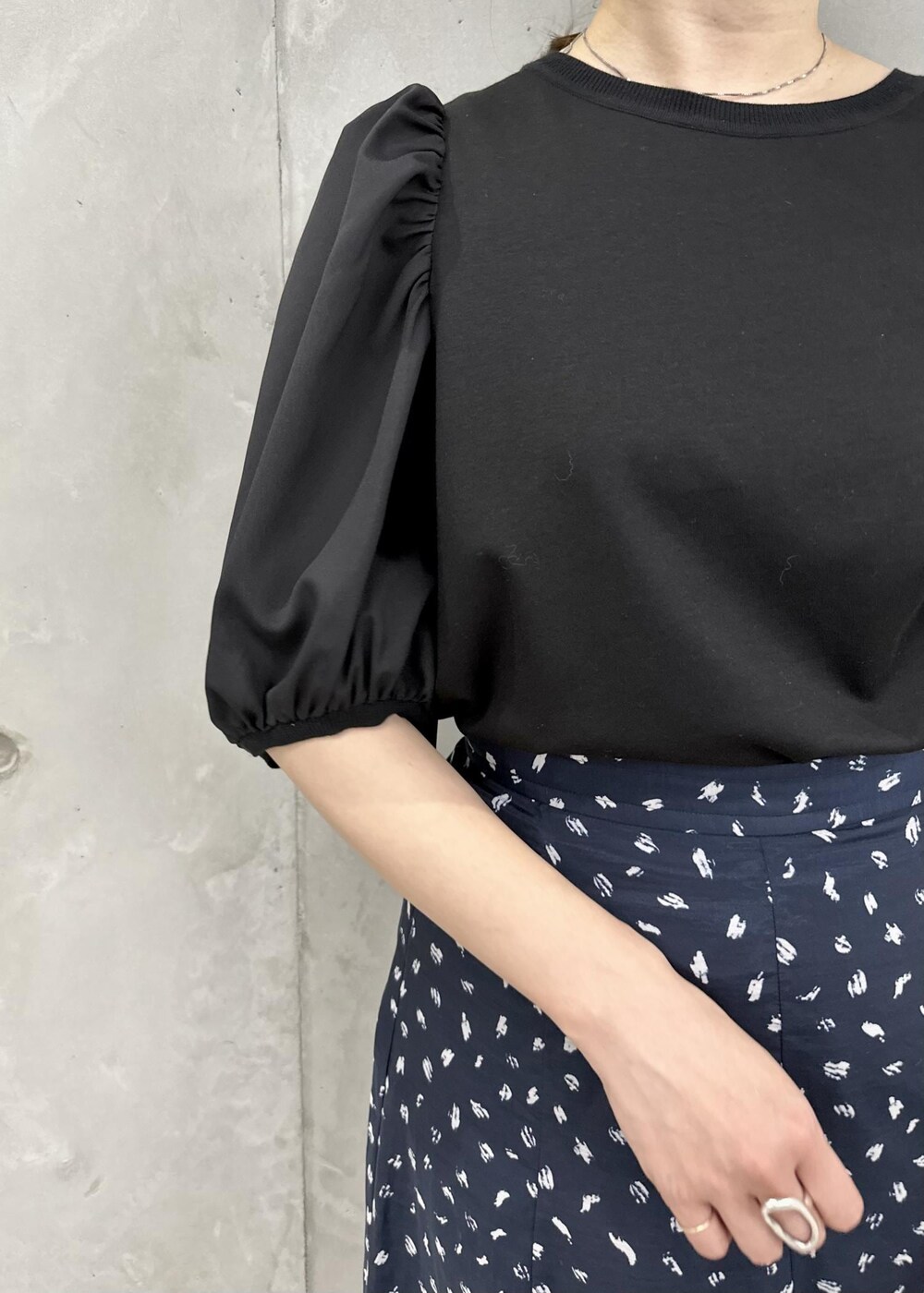 ブラック系のスカート、ホワイト系のハンドバッグ、ホワイト系のサンダルを着用したレディースの春コーディネートの5枚目の写真