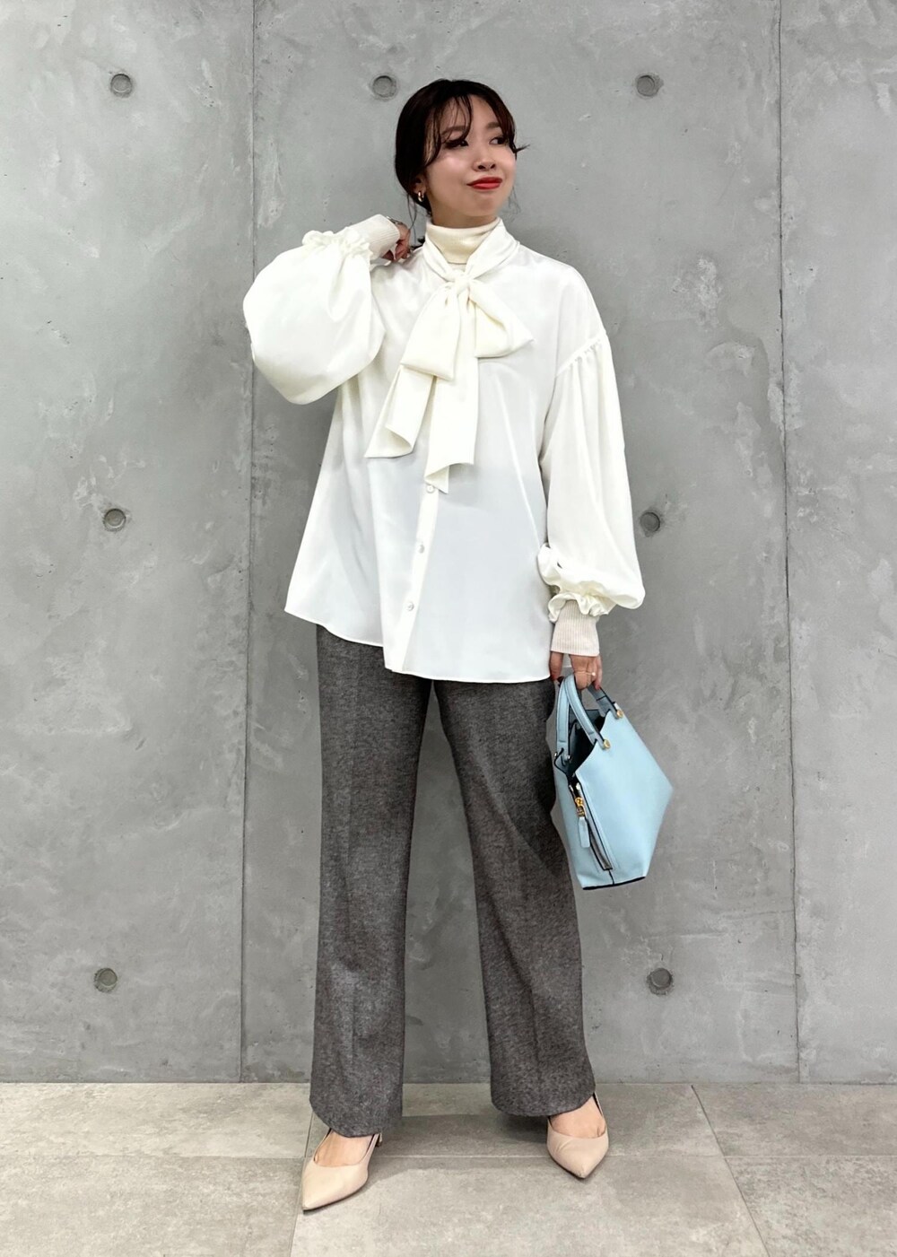 ブルー系のハンドバッグ、ベージュ系のパンプス、グレー系のその他パンツを着用したレディースの秋コーディネートの2枚目の写真