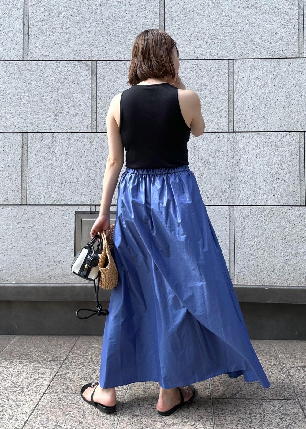 ブラック系のサンダル、ブルー系のスカート、ブラック系のタンクトップを着用したレディースの夏コーディネートの5枚目の写真