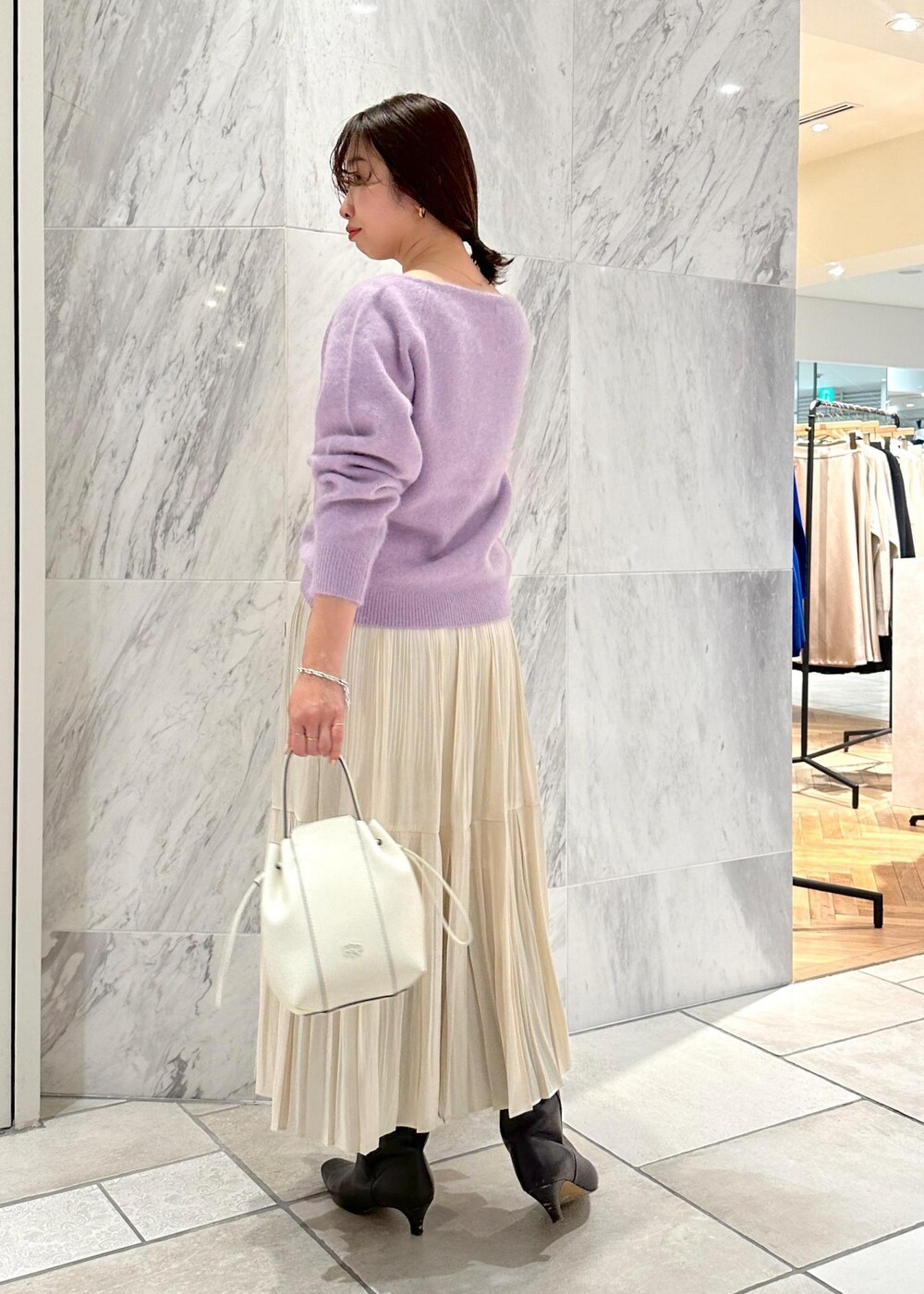 ホワイト系のハンドバッグ、ブラウン系のブーツ、ホワイト系のスカートを着用したレディースの冬コーディネートの3枚目の写真