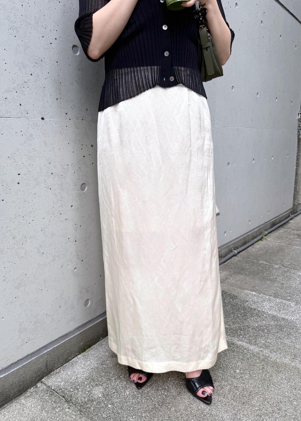 グリーン系のハンドバッグ、ブラック系のカーディガン/ボレロ、ホワイト系のスカートを着用したレディースの夏コーディネートの5枚目の写真