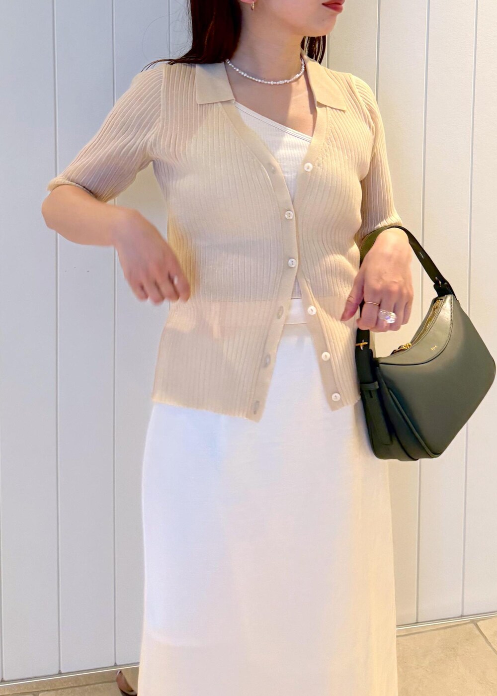 ホワイト系のスカート、ベージュ系のニット/セーター、グリーン系のハンドバッグを着用したレディースの夏コーディネートの6枚目の写真