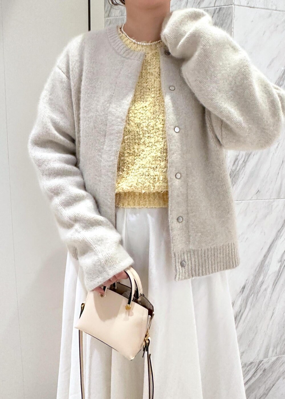 ベージュ系のショルダーバッグ、ホワイト系のカーディガン/ボレロ、ホワイト系のスカートを着用したレディースの冬コーディネートの4枚目の写真