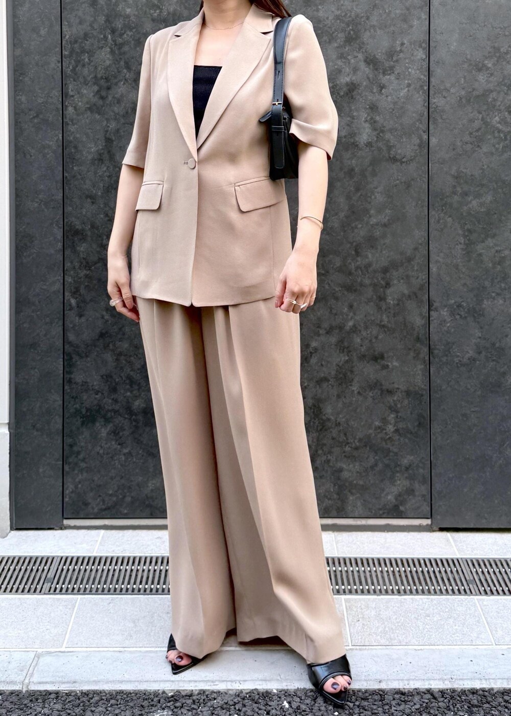ベージュ系のその他パンツ、ベージュ系のテーラードジャケット、ブラック系のハンドバッグを着用したレディースの夏コーディネートの5枚目の写真