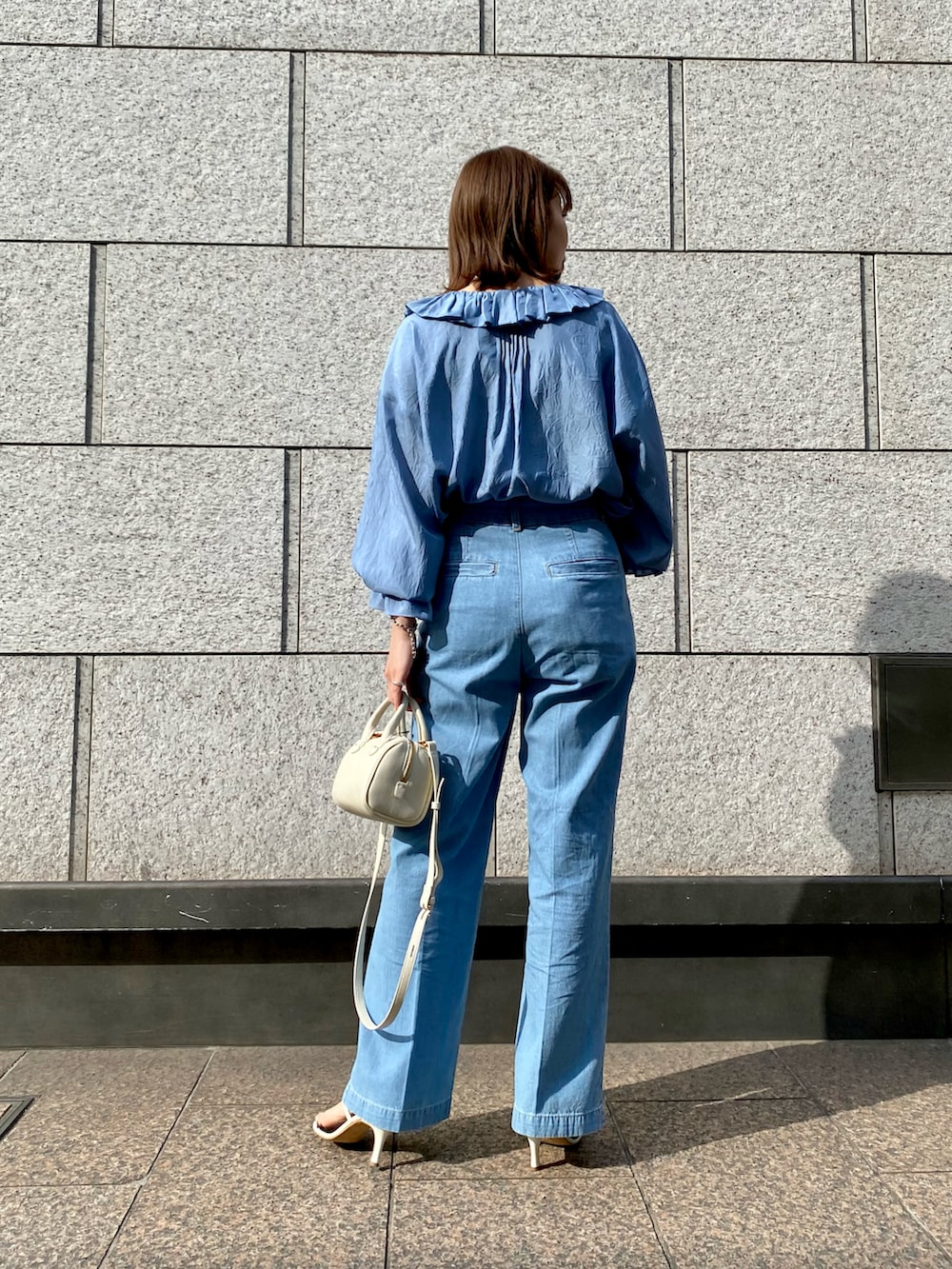 ブルー系のシャツ/ブラウス、ホワイト系のハンドバッグ、ブルー系のデニムパンツを着用したレディースの春コーディネートの2枚目の写真