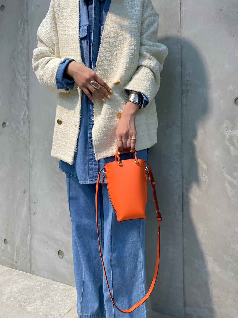 ホワイト系のノーカラージャケット、ブルー系のシャツ/ブラウス、オレンジ系のショルダーバッグを着用したレディースの春コーディネートの4枚目の写真