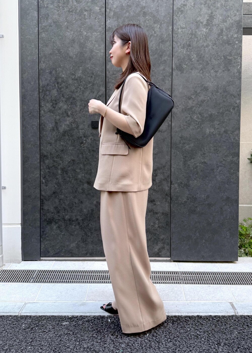 ベージュ系のその他パンツ、ベージュ系のテーラードジャケット、ブラック系のハンドバッグを着用したレディースの夏コーディネートの3枚目の写真