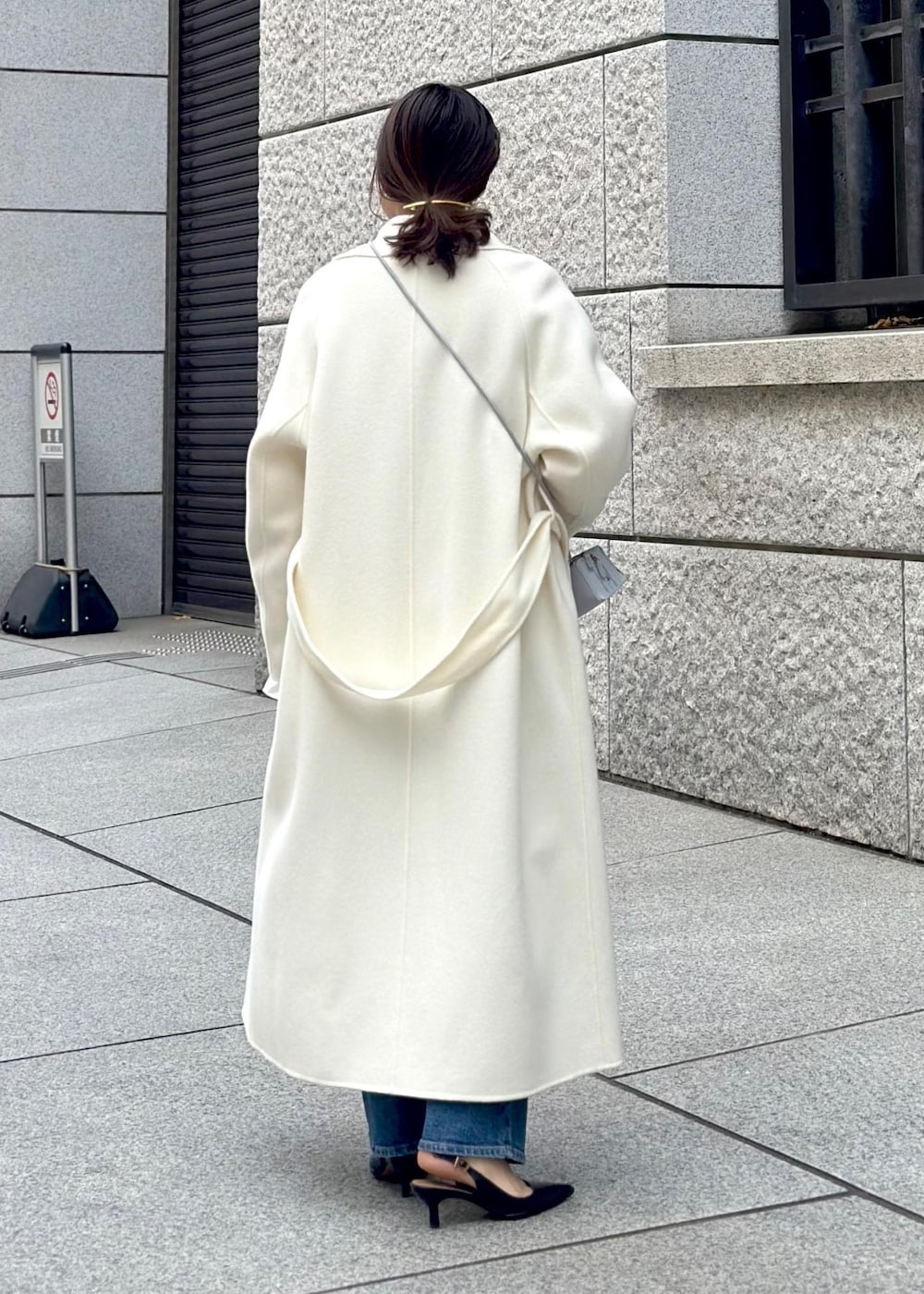 ブルー系のショルダーバッグ、ホワイト系のチェスターコート、ホワイト系のニット/セーターを着用したレディースの冬コーディネートの3枚目の写真