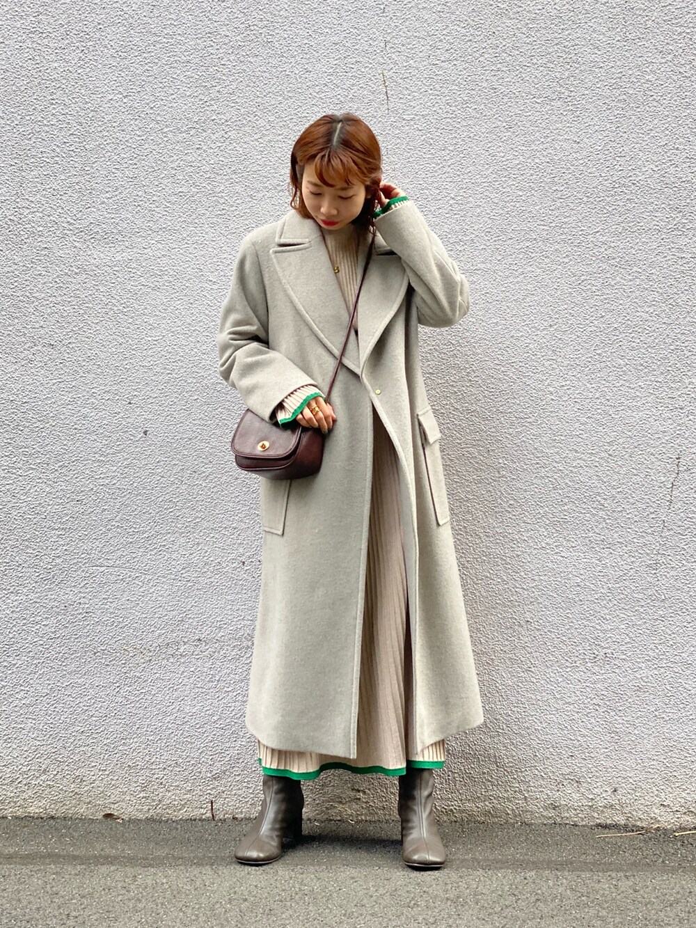 グレー系のチェスターコート、ベージュ系のスカート、ブラウン系のブーツを着用したレディースの冬コーディネートの2枚目の写真