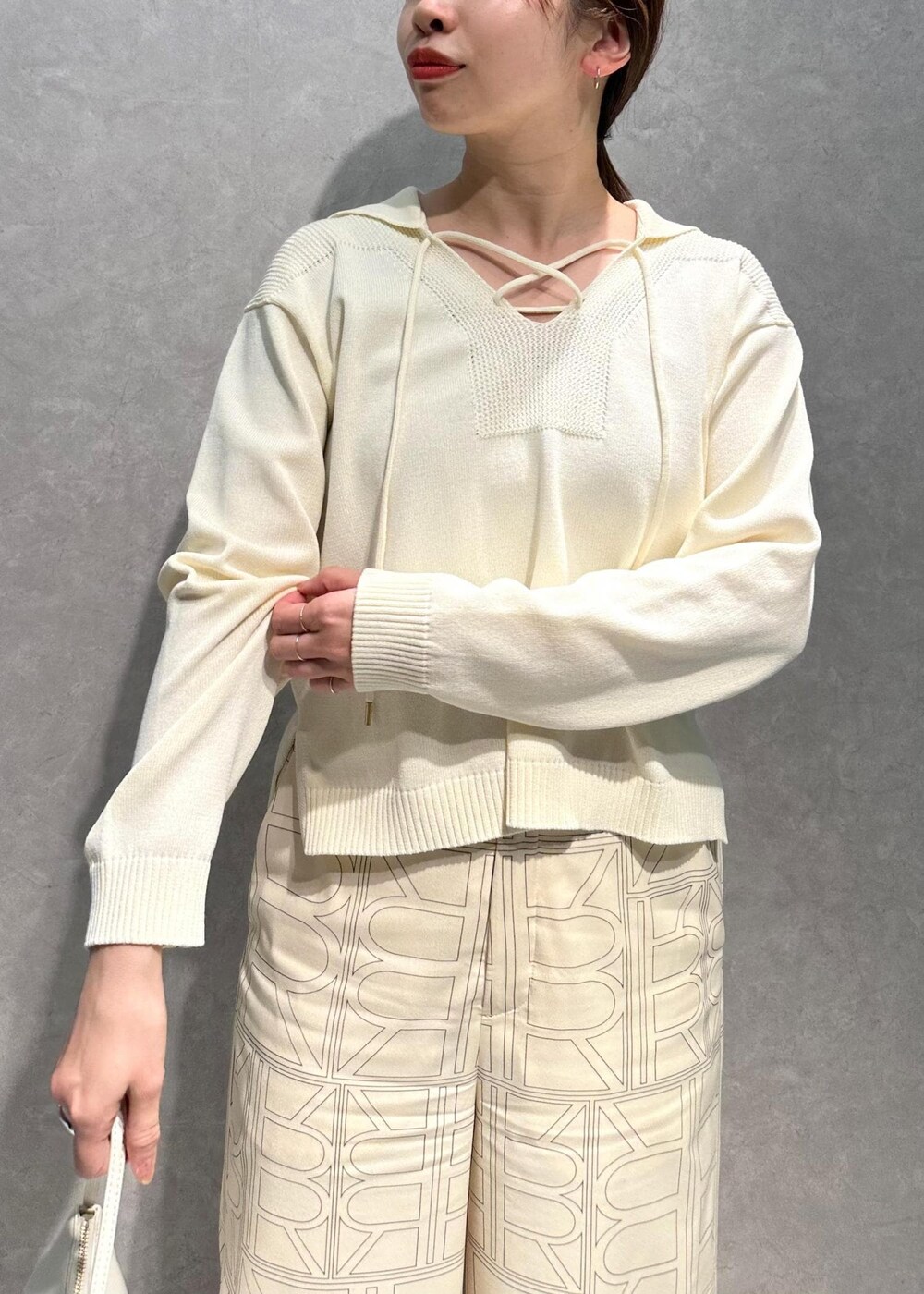 ホワイト系のニット/セーター、ホワイト系のその他パンツ、ホワイト系のハンドバッグを着用したレディースの春コーディネートの5枚目の写真