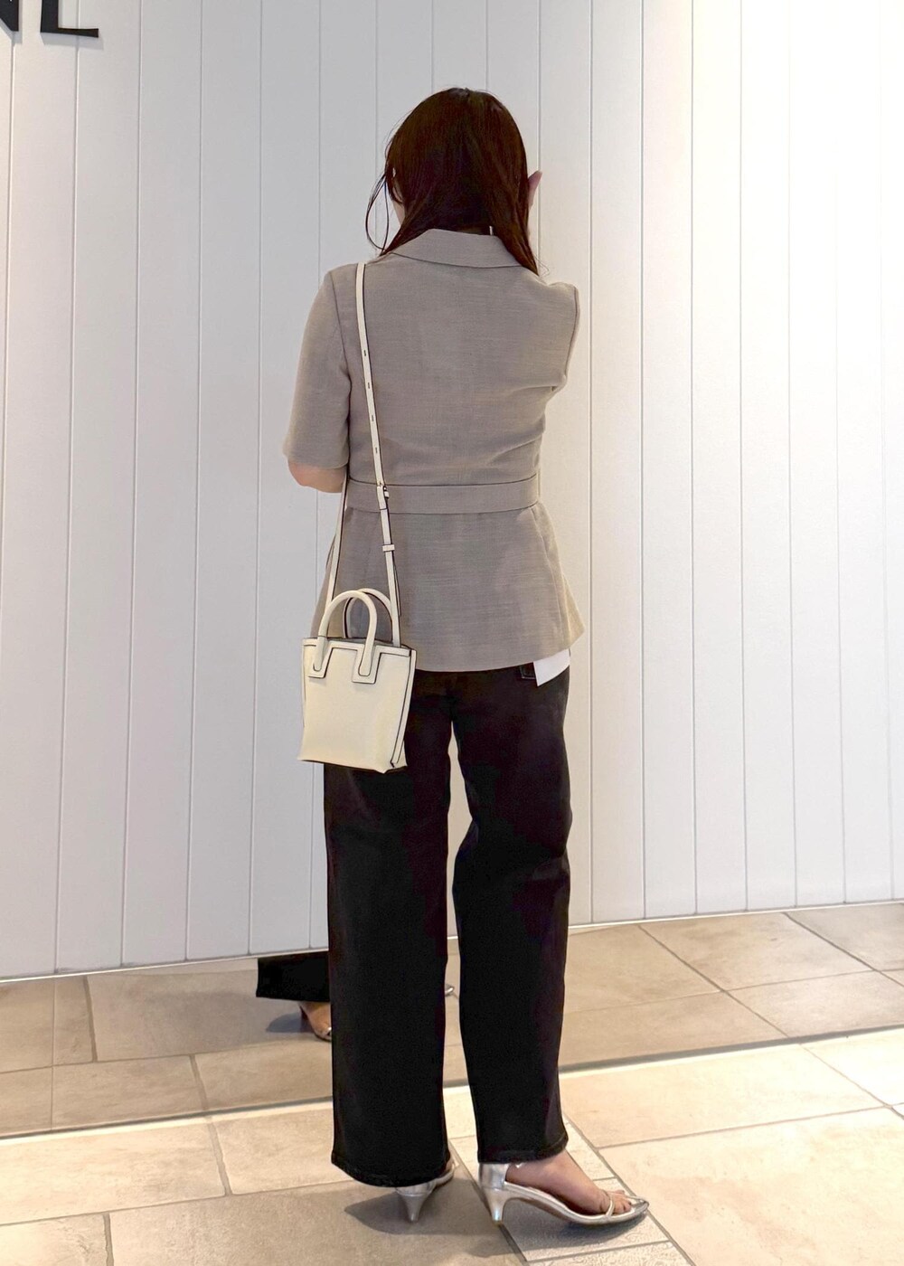 ベージュ系のテーラードジャケット、ブラック系のデニムパンツ、ホワイト系のショルダーバッグを着用したレディースの夏コーディネートの3枚目の写真