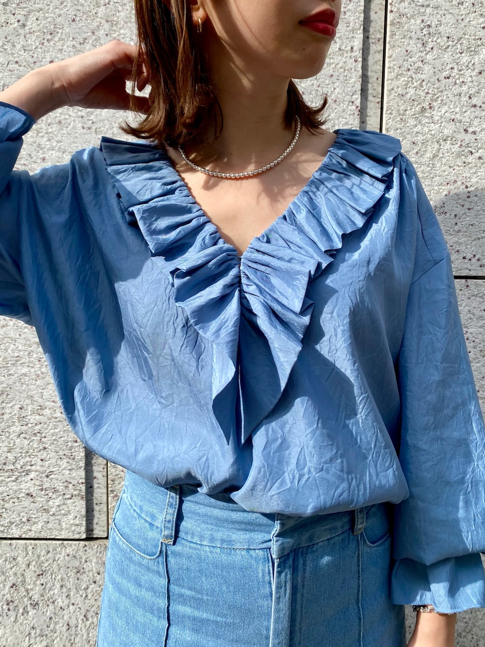 ブルー系のシャツ/ブラウス、ホワイト系のハンドバッグ、ブルー系のデニムパンツを着用したレディースの春コーディネートの3枚目の写真