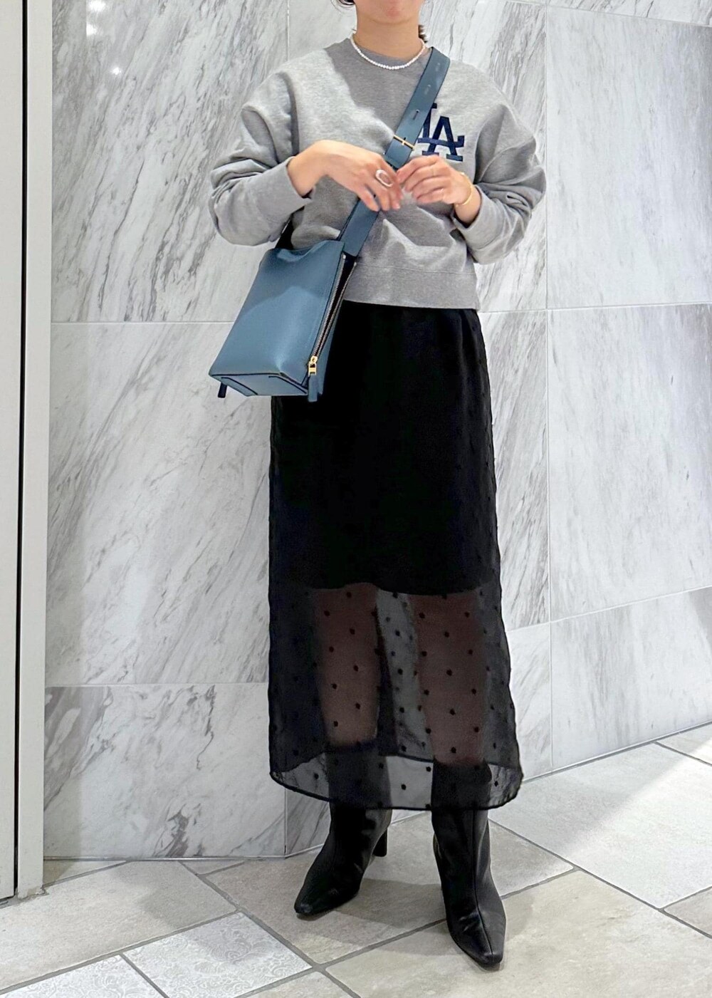 グレー系のスウェット、ブルー系のショルダーバッグ、ブラック系のスカートを着用したレディースの秋コーディネートの10枚目の写真