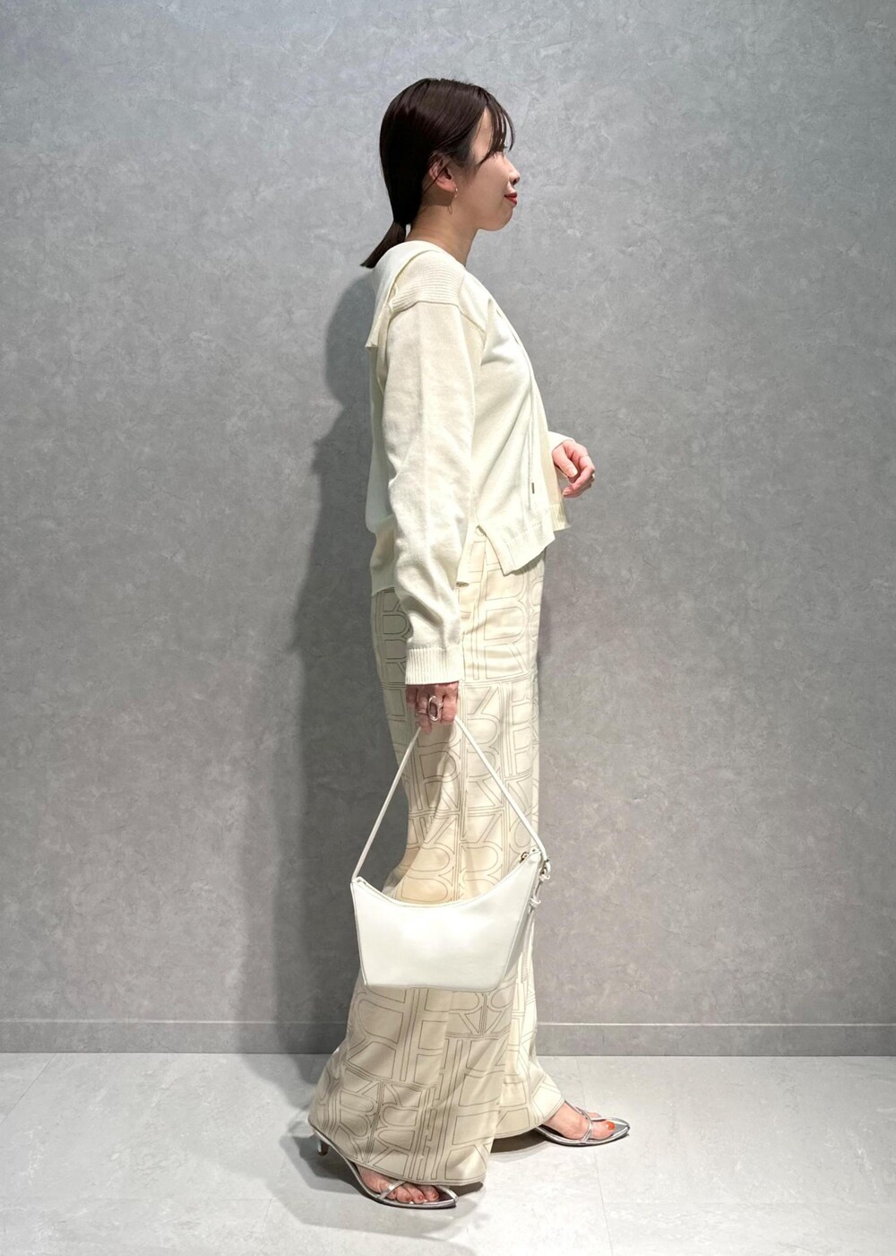 ホワイト系のニット/セーター、ホワイト系のその他パンツ、ホワイト系のハンドバッグを着用したレディースの春コーディネートの3枚目の写真