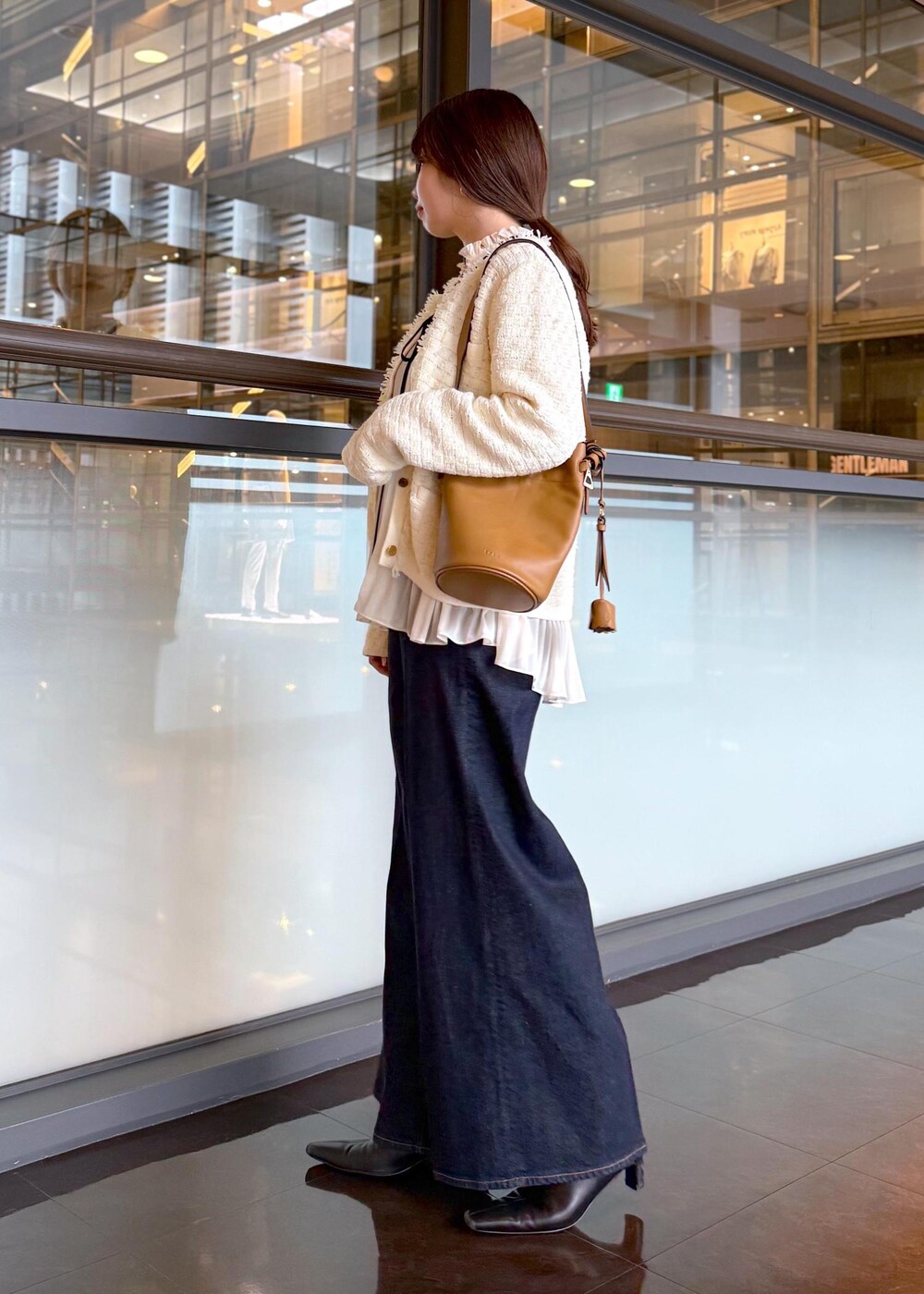 ブルー系のデニムパンツ、イエロー系のハンドバッグ、ホワイト系のノーカラージャケットを着用したレディースの秋コーディネートの3枚目の写真