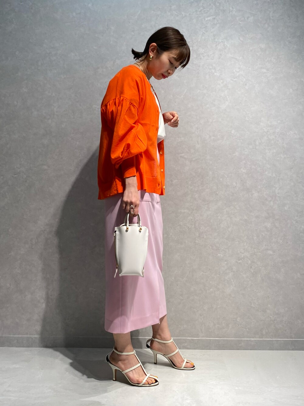 ホワイト系のショルダーバッグ、ホワイト系のサンダル、ピンク系のスカートを着用したレディースの春コーディネートの2枚目の写真